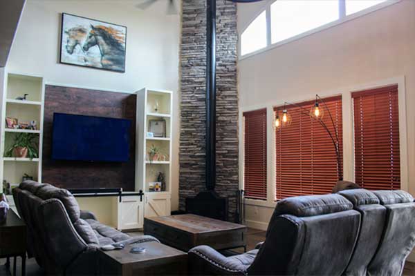 living room with stone wood burning fireplace and large entertainment center=