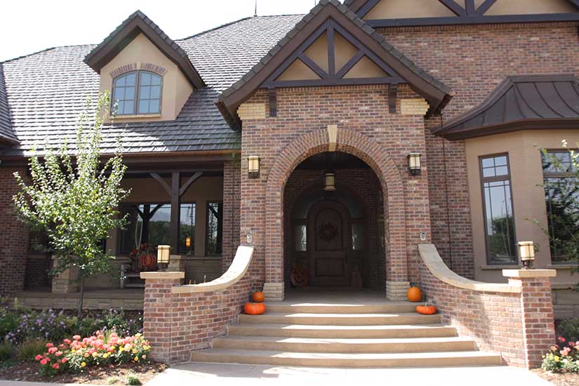 front entrance with curved brick fense, brick archway and wood trusses