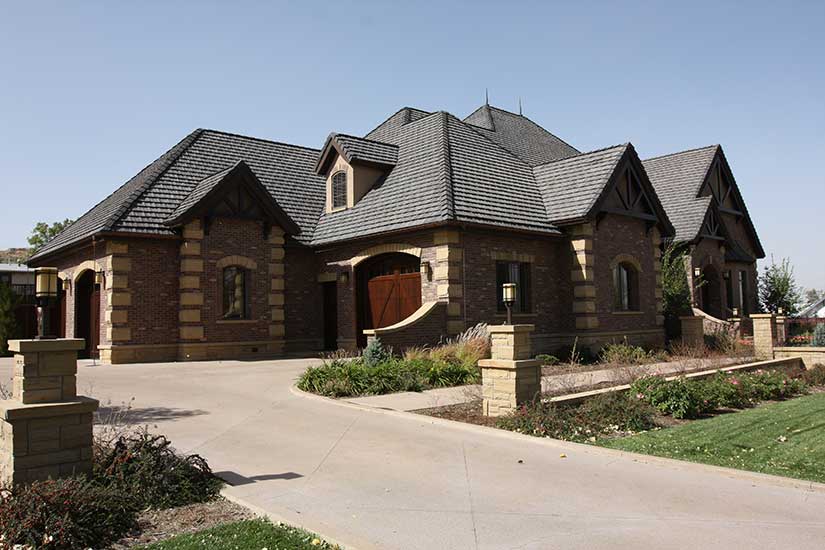 side of house has wood garage door, chain drop rain gutter and stone accents