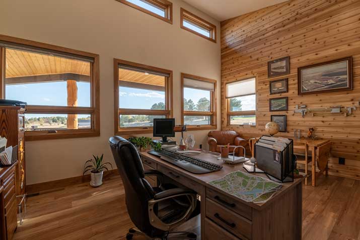 vaulted ceiling office with wood accent wall and large windows