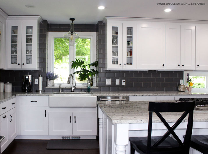 farm sink with white shaker glass cabinets and matt gray subway tile